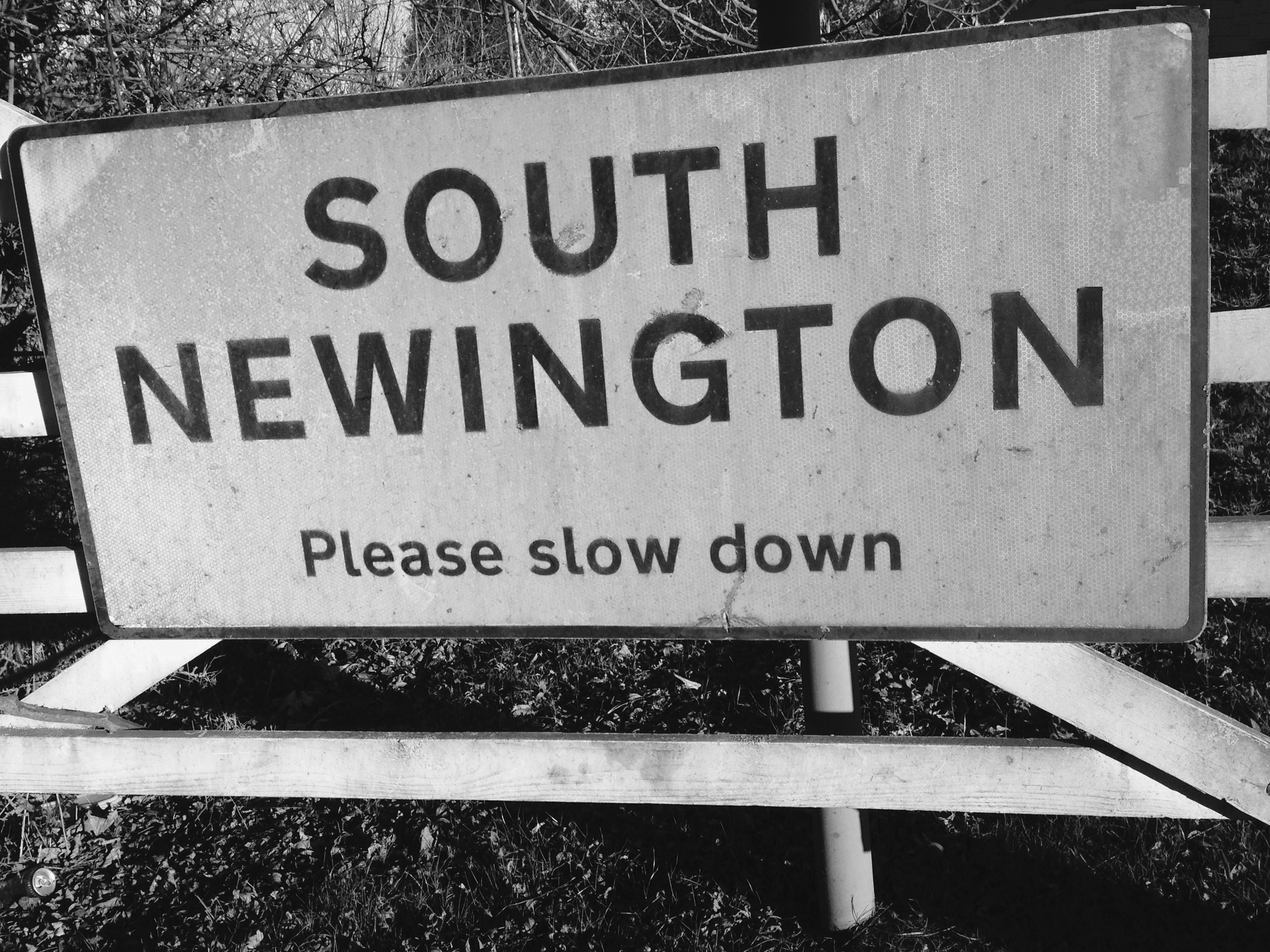 Close-up of sign reading "South Newington: Please slow down"