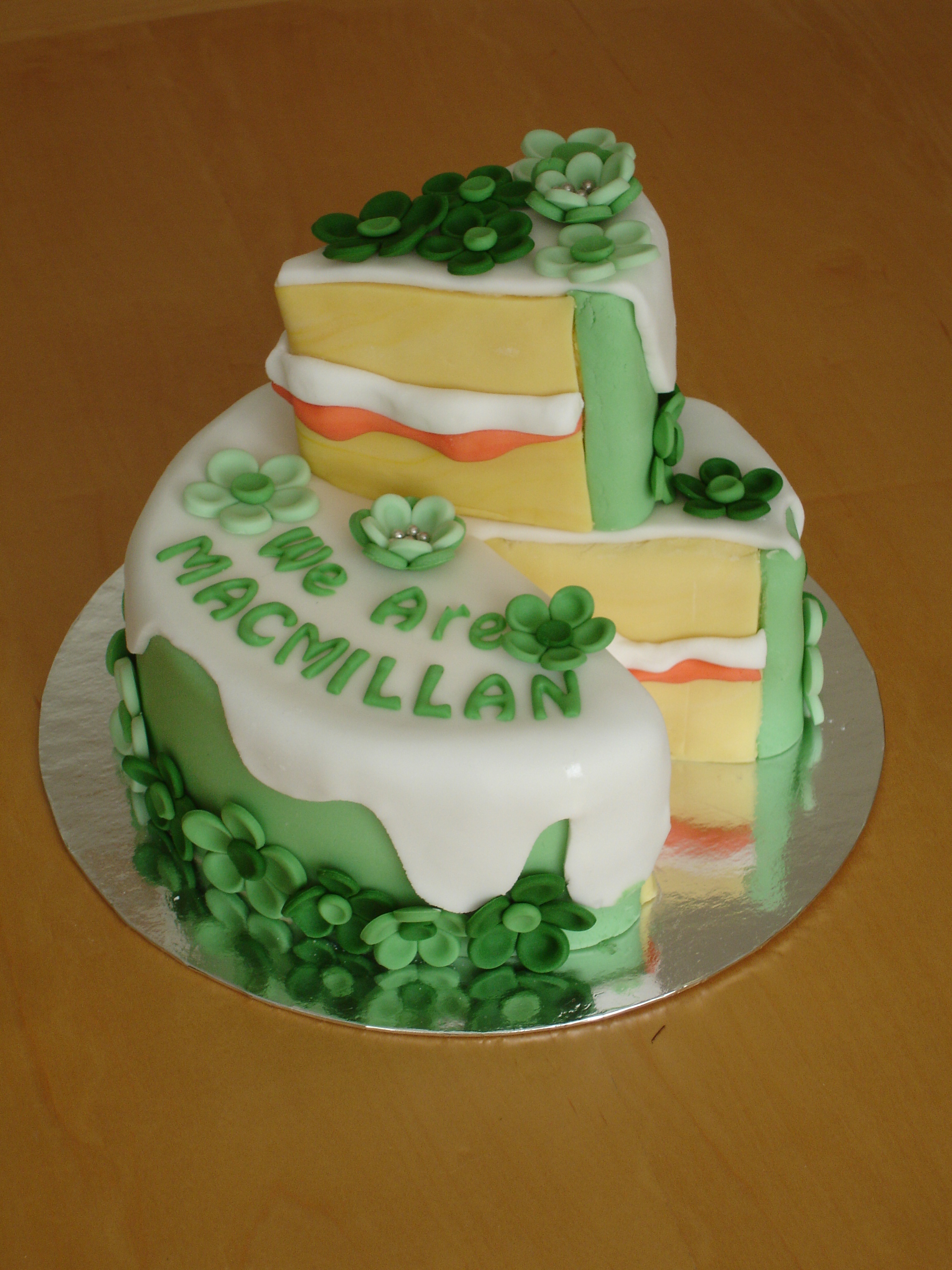 A white cake decorated with green icing the words "We Are MacMillan"